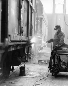 171714 Afbeelding van een lasser in de hoofdwerkplaats (wagenwerkplaats) van de N.S. te Amersfoort.